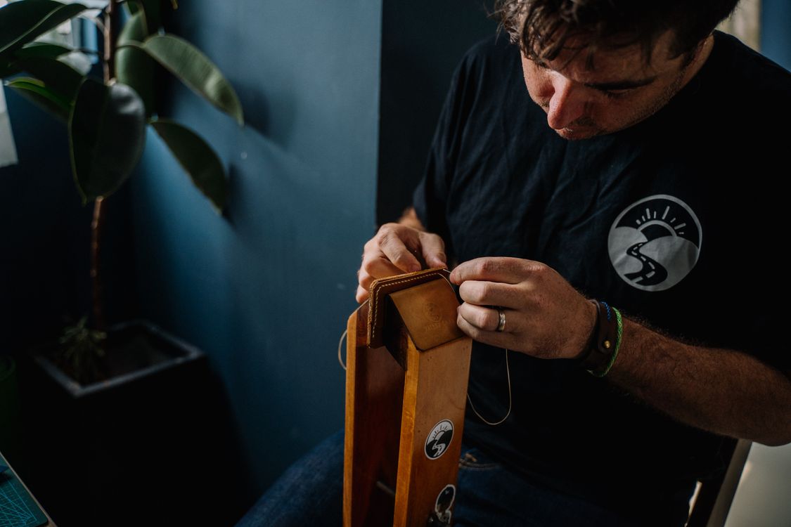 Artisan stitching a leather accessory by hand